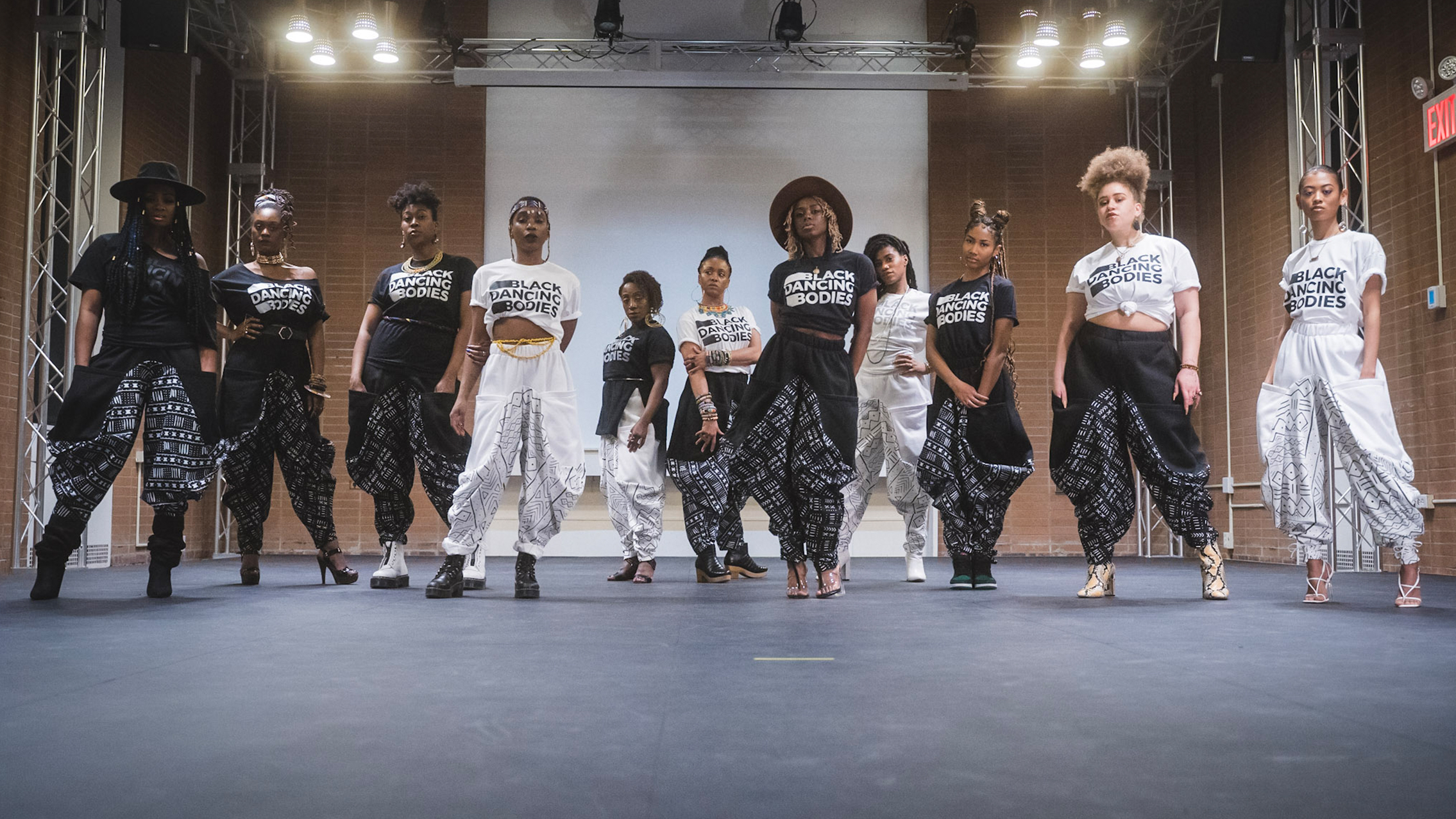 Ladies of Hip-Hop Dance Collective stand on an indoor stage facing the camera.