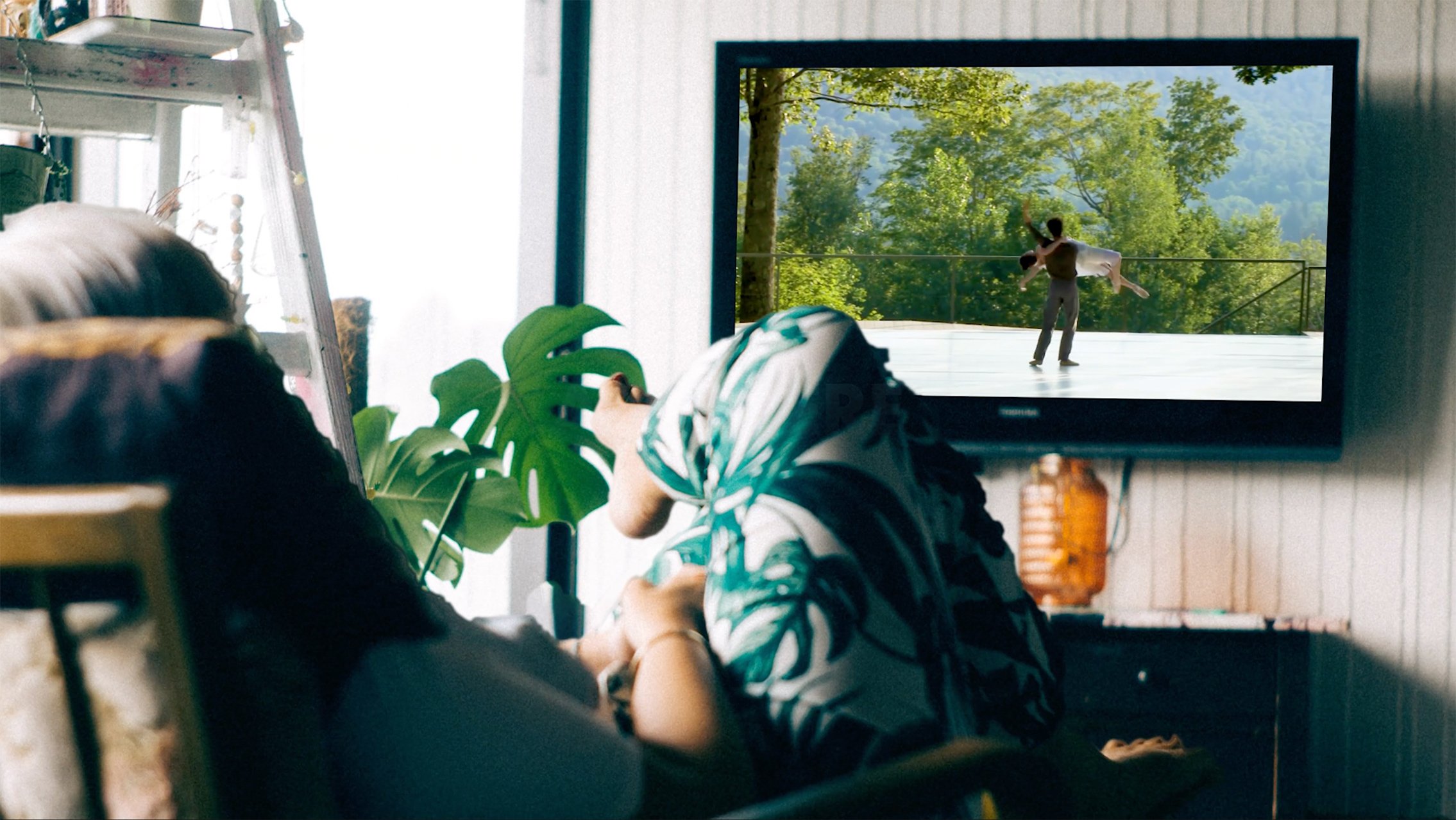 Person sitting on couch watch a Jacob's Pillow dance performance on their TV.