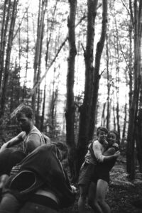 Black and white photo of people dancing in the woods.