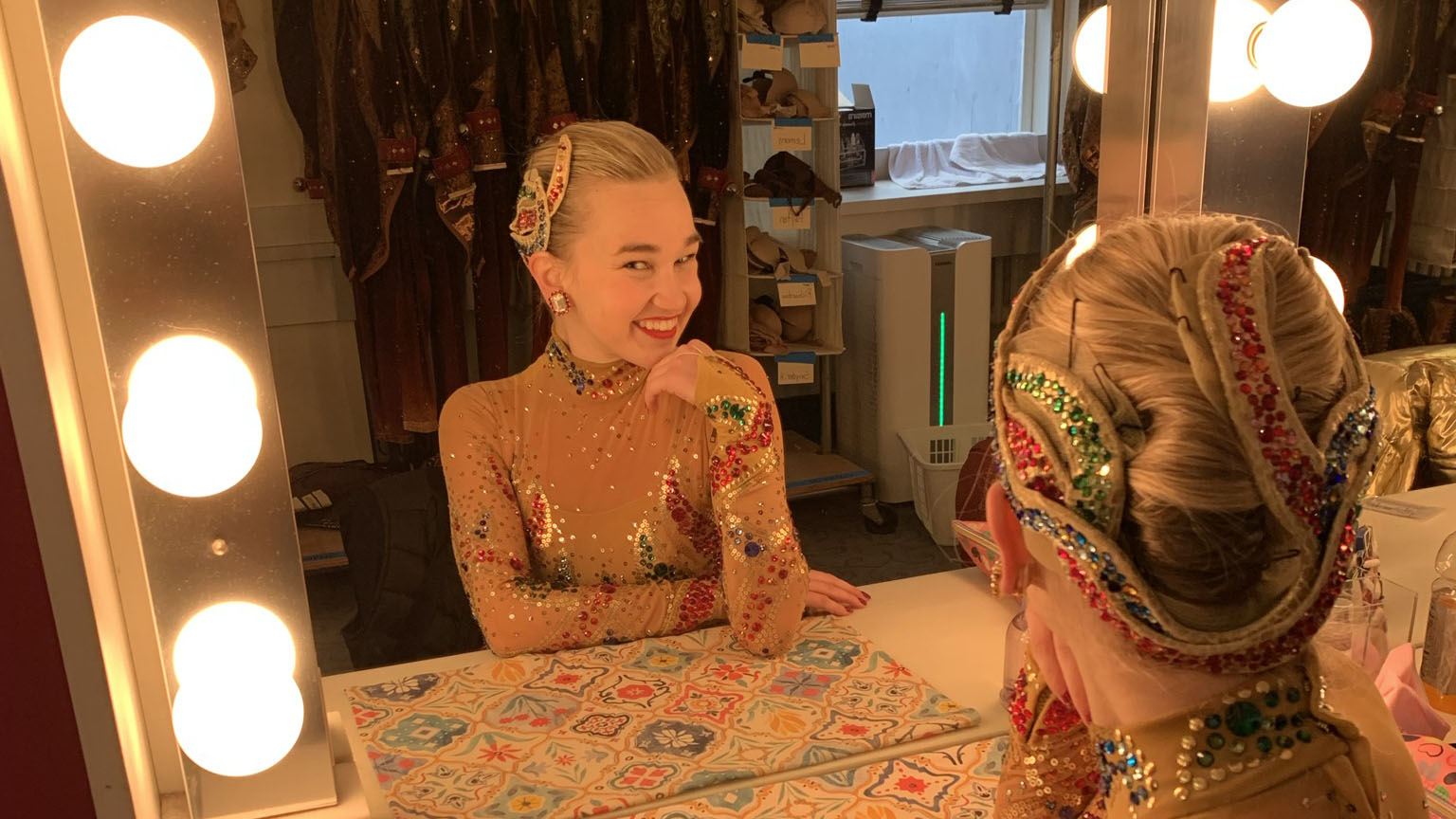 Kathleen Laituri grins at herself in the mirror, resting her chin on her right hand. She's in The Rockettes' dressing room, wearing a sequined holiday costume.