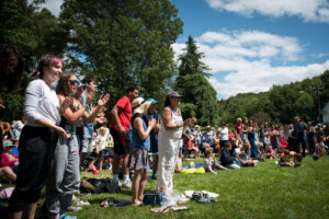 A large audience assembled on a lawn clap.