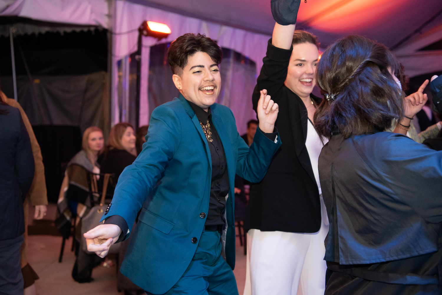 A person wearing a blue suit dances and smiles.