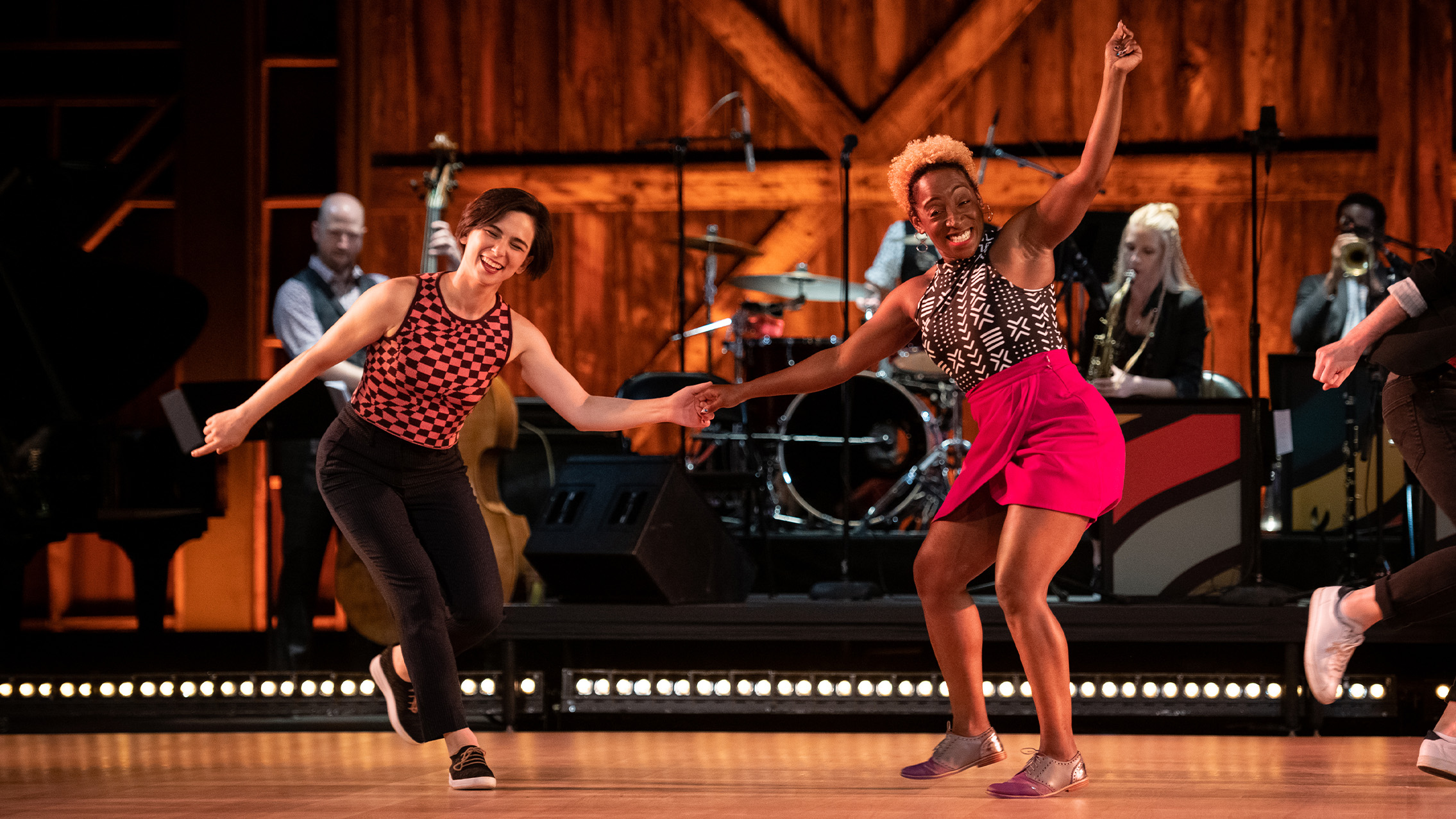 Two dancers holding hands swing dancing.