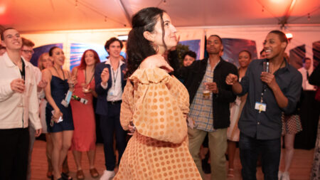 A person in an orange dress dances among a crowd of people.