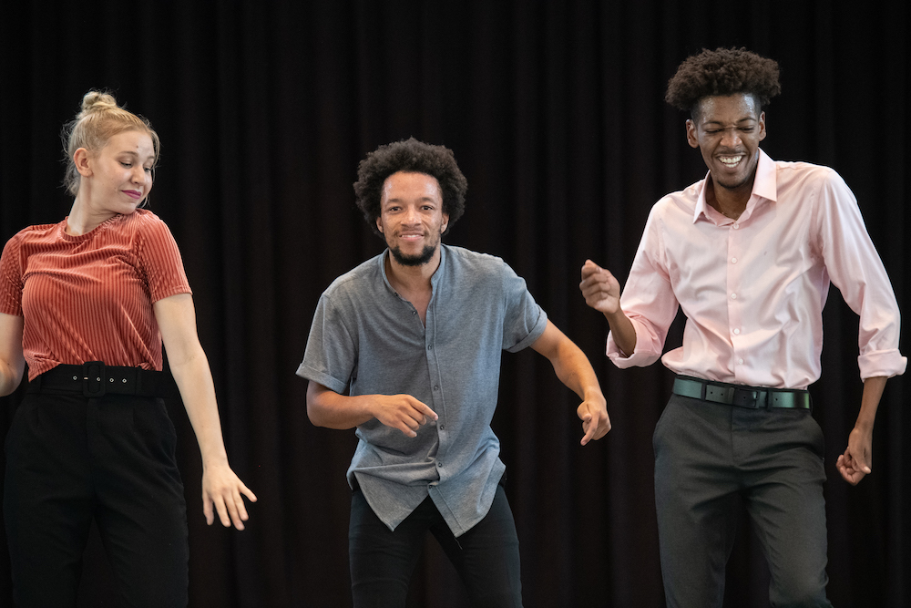 Sterling Harris and 2 other dancers smile while tap dancing.