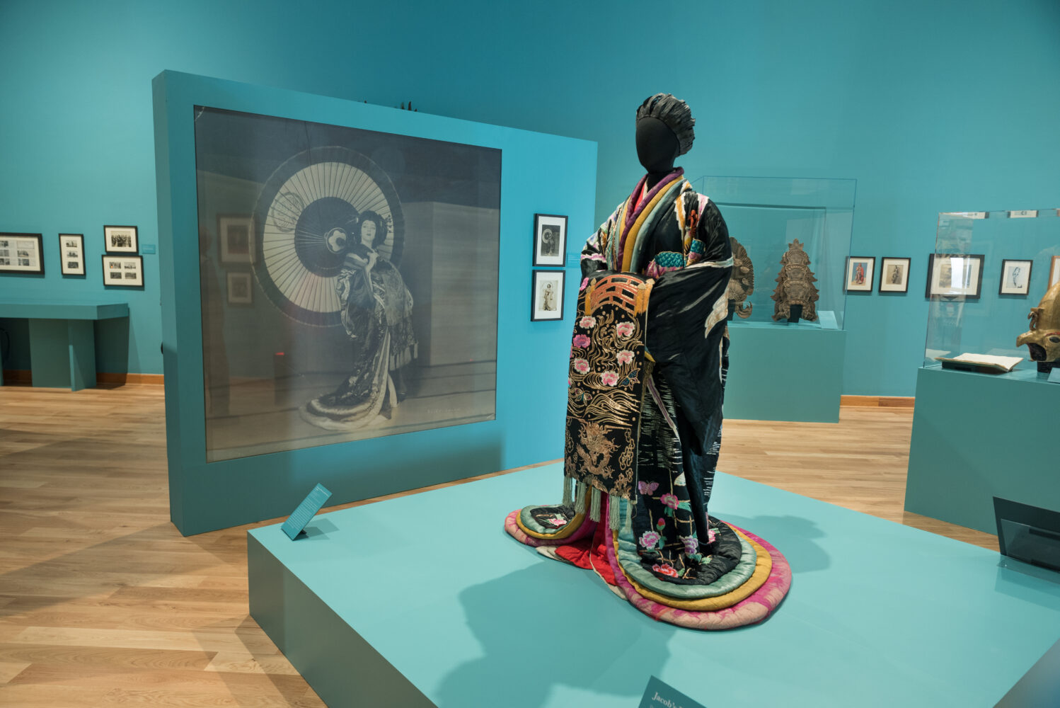 A Japanese kimono is displayed on a statue in an art gallery with blue walls.