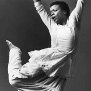 Black and white photo of Blondell Cummings throwing her arms over head. She looks over her right shoulder at her right foot.
