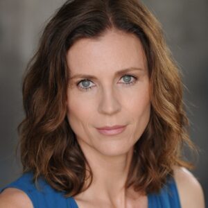 Headshot of Nadia Adame smiling. She has brown shoulder-length hair and green/blue eyes. She wears a blue sleeveless blouse