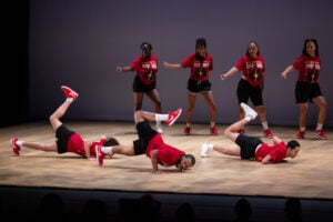 Members of the KR3TS Dance Company dance and snap in union as other members of the company break on the floor infront of them.