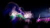 Dancers appear in a green, blue, and purple blur